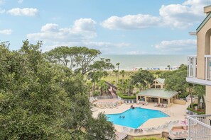 A pool area with a view of the beach and ocean.
