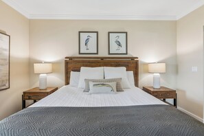 A hotel room with a large bed, two nightstands, a wooden headboard, and two framed wall art pieces.