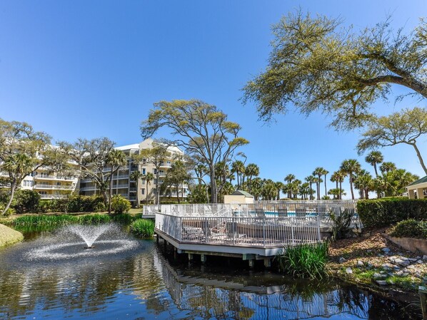 A waterfront view with a pool, palm trees, and a building with balconies.