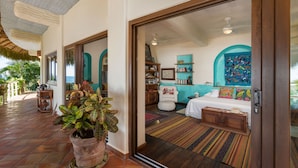 A spacious room with a large bed, a sitting area with a chair, and a view of the ocean through a large window. - Secluded Beachfront Sanctuary w/ Epic Sunsets & Palapa Lounge (Higuera Blanca)