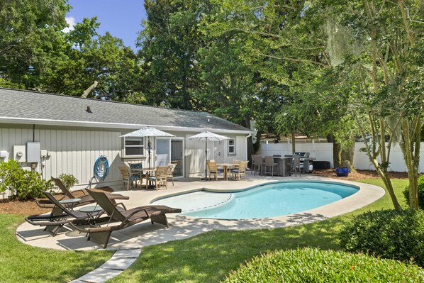 A backyard with a swimming pool, lounge chairs, and a patio area. - Stunning Beach Home/Private pool with large backyard/ 7 Min walk to beach (Hilton Head Island)