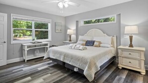Une chambre à coucher comprenant un lit, des tables de chevet, un bureau et un ventilateur de plafond.