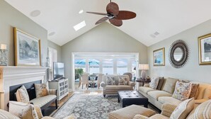 A spacious living room with a fireplace, comfortable seating, and a view of the outdoors. - Enjoy the Amazing Views from this Beach Cottage (Hilton Head Island)