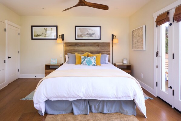 A bedroom with a large bed, two bedside tables, a wooden headboard, and two wall-mounted lamps.