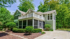 Une maison à deux étages avec un balcon, une véranda et un garage.