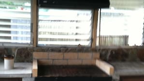 A kitchen with a built-in grill, a window with blinds, and a stone wall. - Three Bedroom House on Private Lake Delancy in Ocala National Forest (Salt Springs)