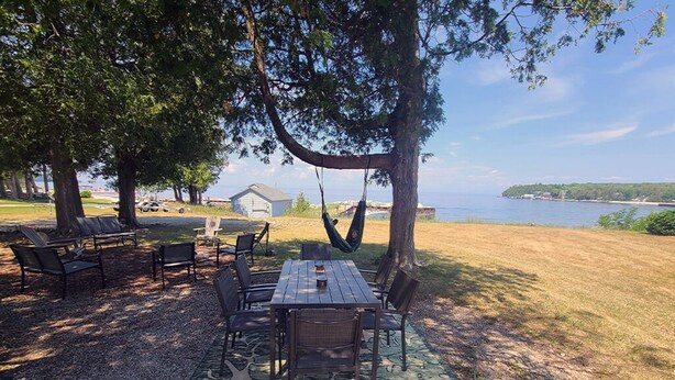 Een terras met een tafel en stoelen, een hangmat, en uitzicht op het water en gebouwen in de verte.