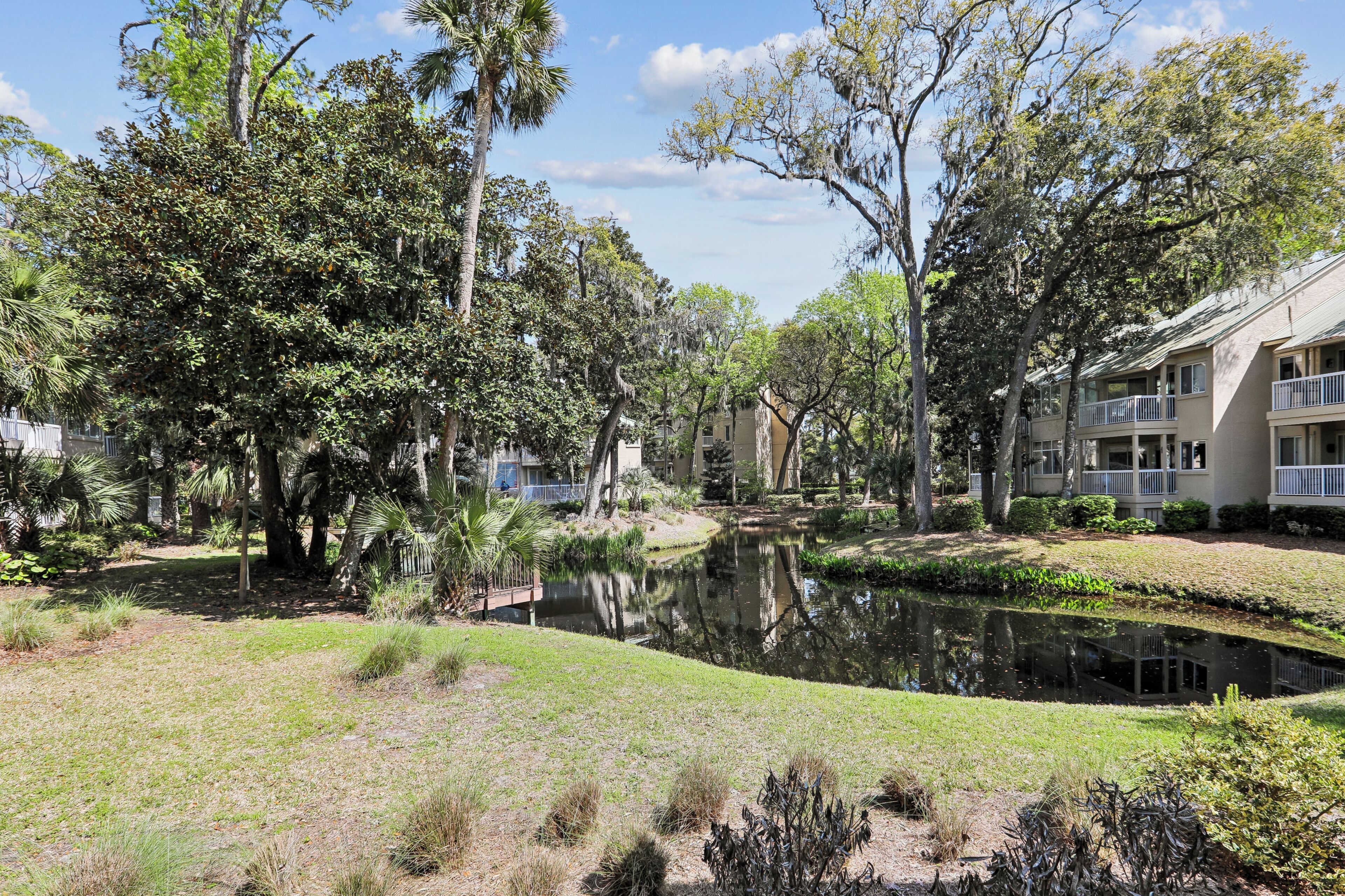 Un quartier résidentiel avec un étang, des arbres et des immeubles à plusieurs étages dotés de balcons.