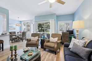 A living room with a sofa, two armchairs, a coffee table, and a TV stand.
