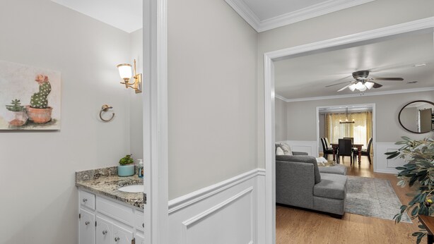 Ein modernes Wohnzimmer mit grauem Sofa, einem Essbereich mit einer Chandelierleuchtre und einer Küche mit weißen Schränken und Granit-Arbeitsplatten.