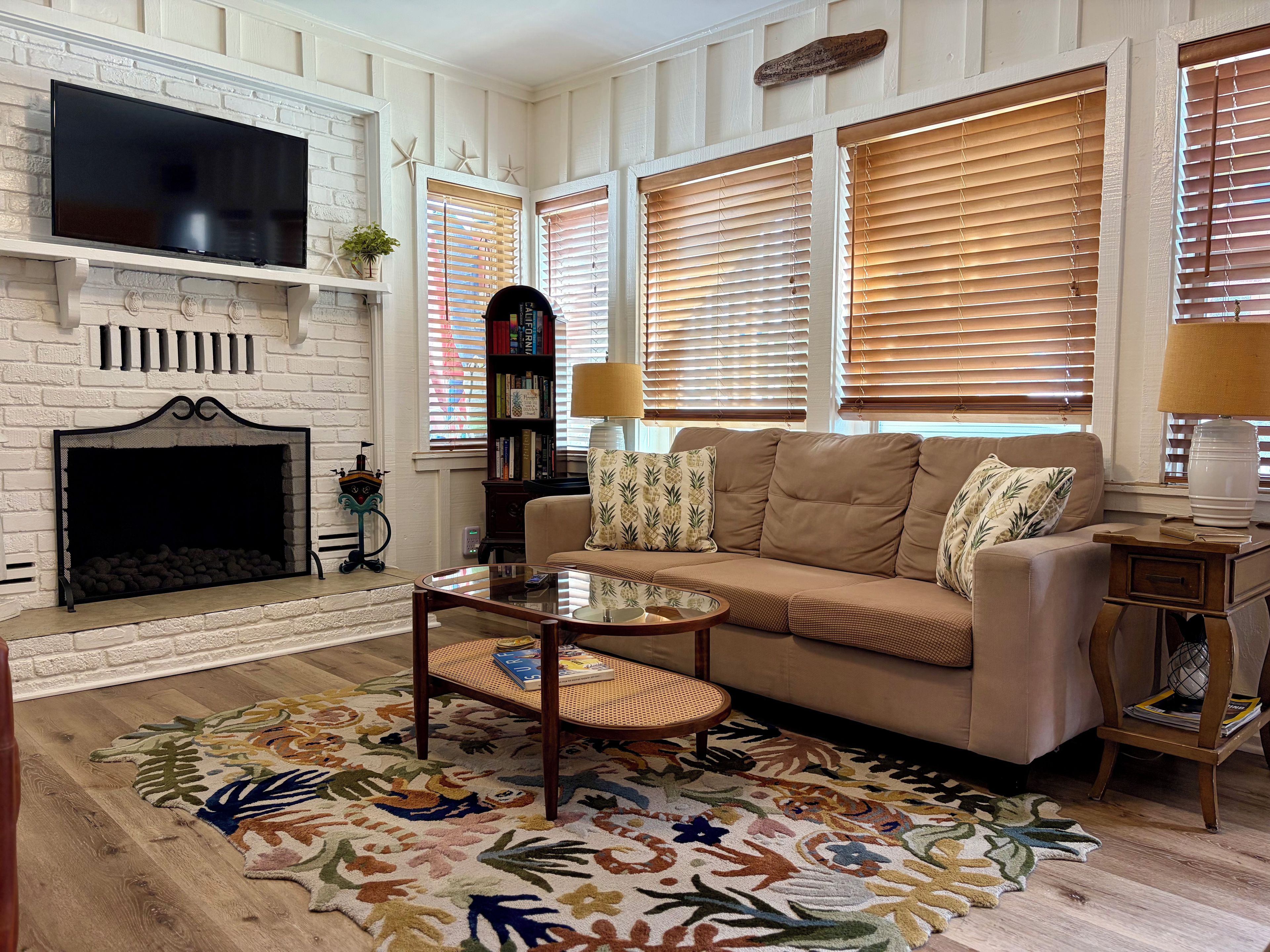 A living room with a fireplace, sofa, coffee table, and a patterned rug.