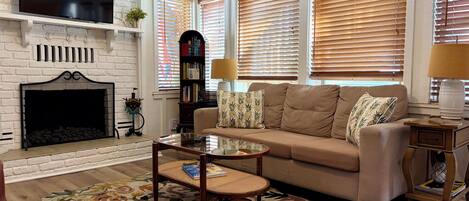 A living room with a fireplace, sofa, coffee table, and a patterned rug.