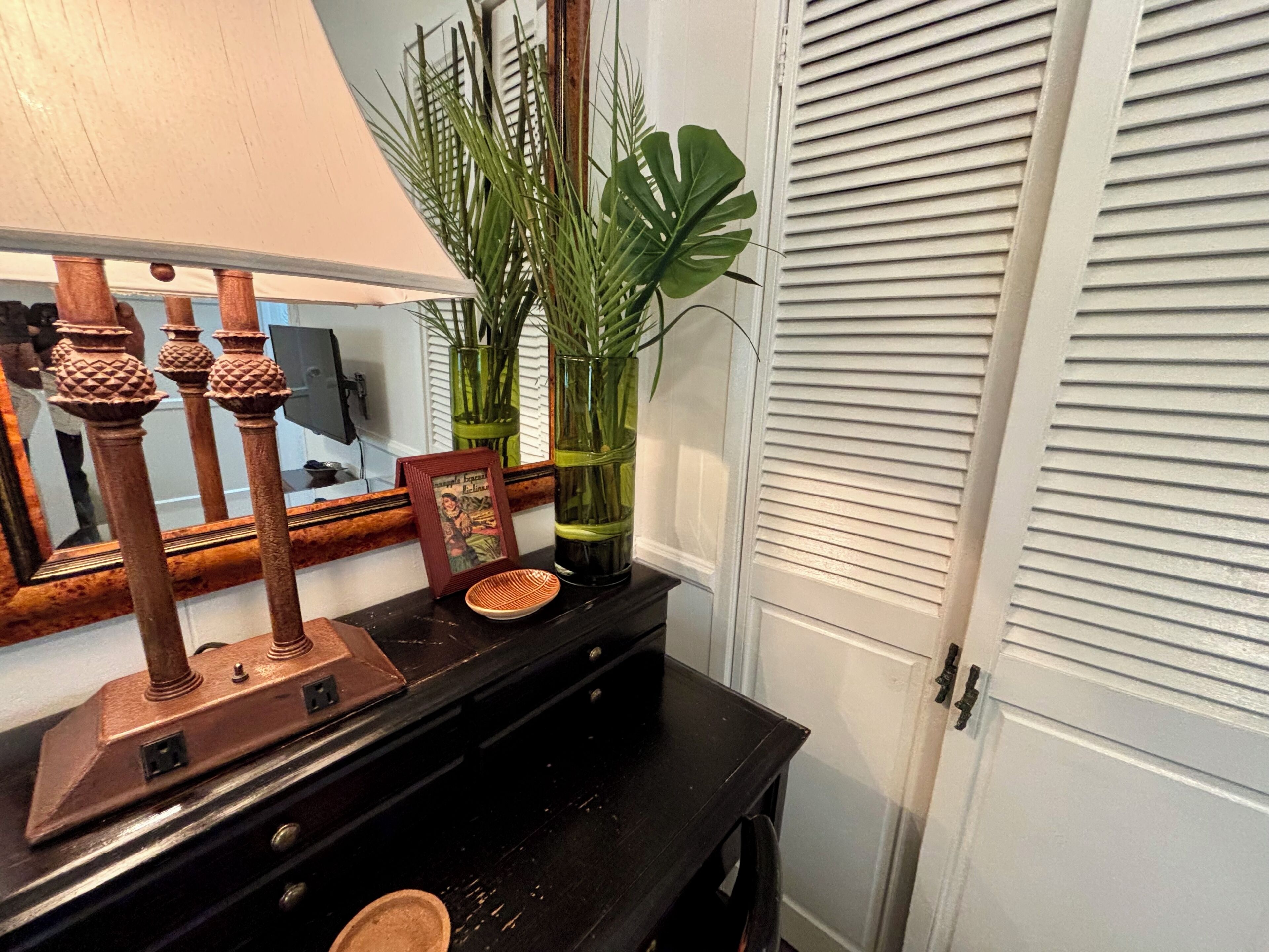 A wooden console table with a lamp, framed picture, and decorative items.