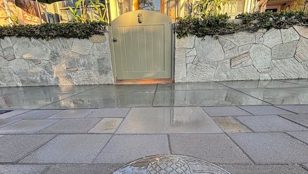 A manhole cover with a pineapple design, a stone wall, and a building with a wooden door and a pineapple decoration. - 🌊🌊 2026 @  the Pineapple Cottage. Steps to Ocean. 🌊 RELAX & ENJOY 😎the beach.⛱️🌊🌊 (Seal Beach)