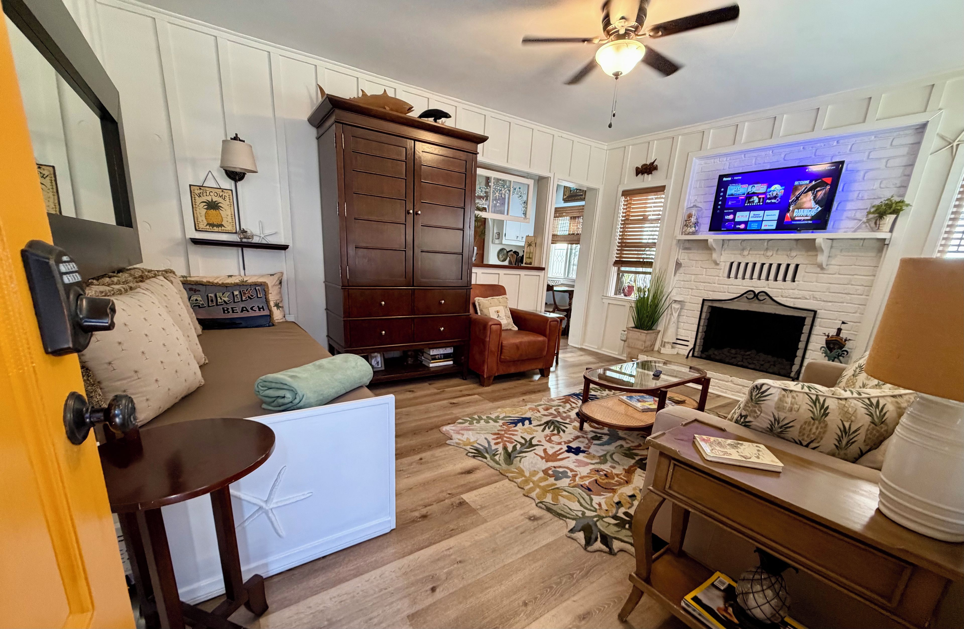 Un salon chaleureux avec une cheminée, un téléviseur fixé au-dessus, un meuble en bois et un coin salon confortable avec un canapé et des fauteuils.