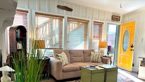A living room with a beige sofa, a green coffee table, a floral rug, and a yellow door. - 🌊🌊 2026 @  the Pineapple Cottage. Steps to Ocean. 🌊 RELAX & ENJOY 😎the beach.⛱️🌊🌊 (Seal Beach)