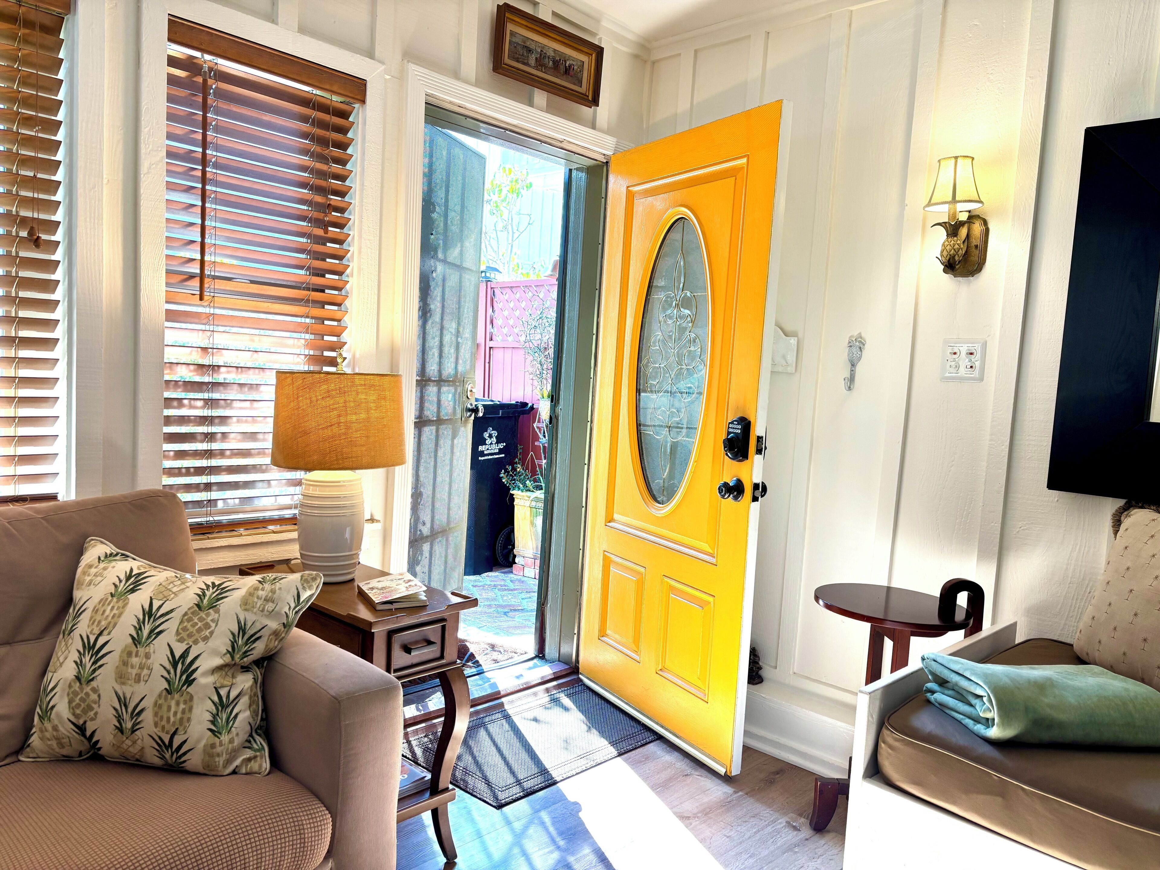 A living room with a sofa, a coffee table, a lamp, a television, and a door with a screen door.