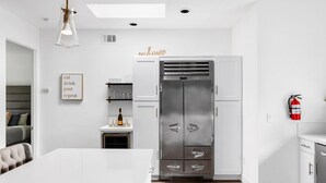 Eine moderne Küche mit einem großen, edlen Kühlschrank aus Edelstahl, weißen Schränken und einem Essbereich mit einem weißen Tisch.