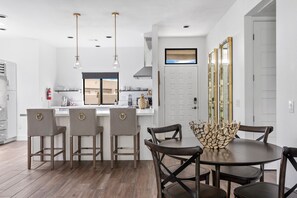A modern kitchen with a central island, bar stools, and pendant lighting.