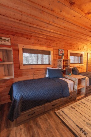 Une chambre dans une cabane en bois, avec un lit, une petite table et une fenêtre.