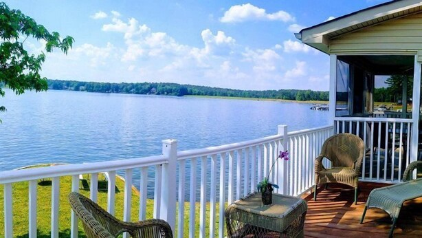 Una terraza con mobiliario de mimbre y vistas a un lago.