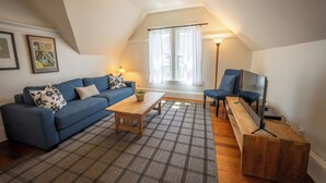 Una sala de estar acogedora con un sofá azul, una mesa de centro de madera y un tapete de cuadros.