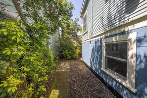 Stroll through the beautifully maintained garden, surrounded by lush foliage and trees, to this charming residence with a large window offering a view of the serene surroundings.