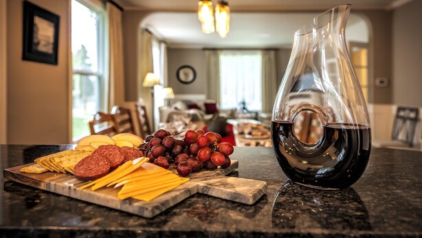 A kitchen counter with a charcuterie board, including sliced meats, cheese, and grapes, and a bottle of red wine. - Walla Walla Gem - Peaceful, Private and a Perfect Central Location  (Walla Walla)