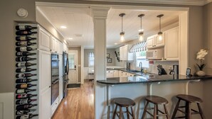A modern kitchen with white cabinetry, a central island with stools, and a wine rack on the left. - Walla Walla Gem - Peaceful, Private and a Perfect Central Location  (Walla Walla)