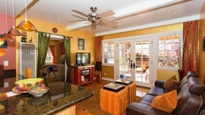 A living room with a dark leather sofa, a coffee table, a television, and a ceiling fan. - Fabulous Downtown Living (Santa Barbara)