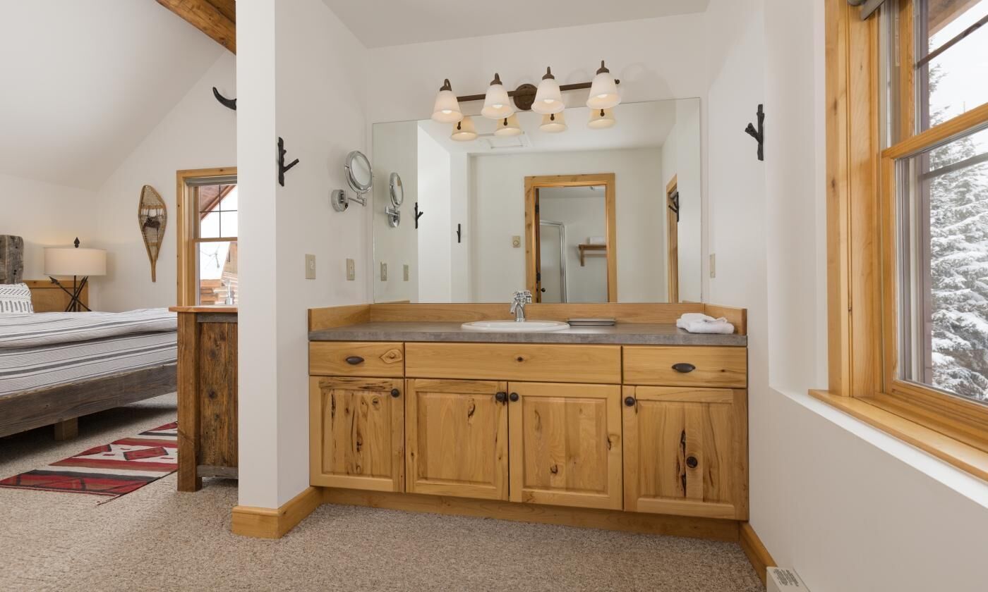 A bathroom with wooden cabinets, a sink, and a mirror.
