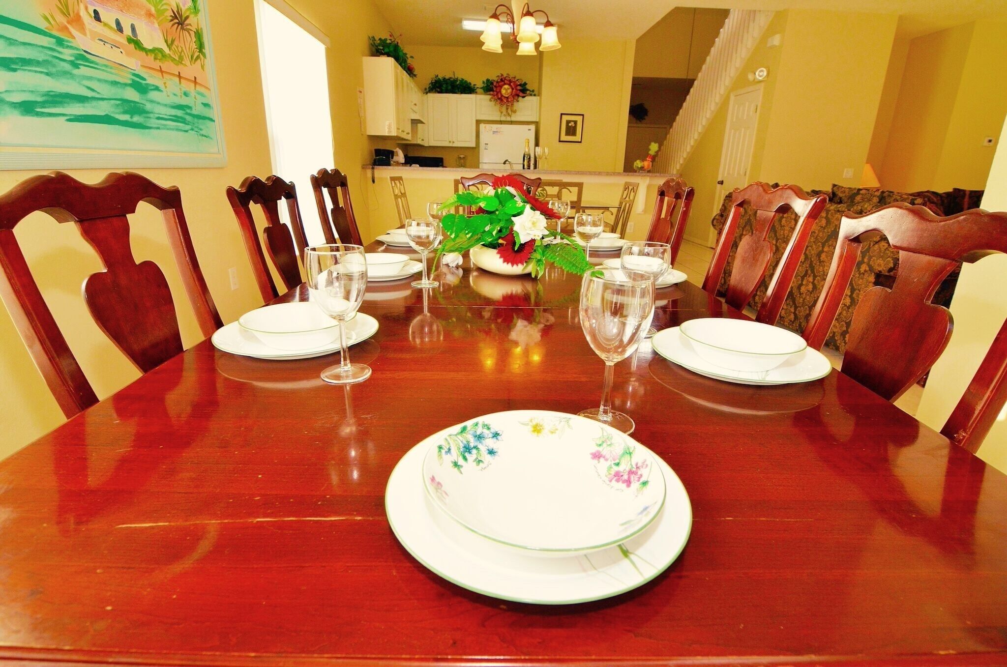 Una mesa de comedor dispuesta con platos, vasos y un centro de mesa.