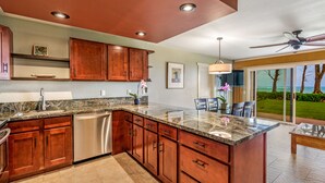 A modern kitchen with wooden cabinets, stainless steel appliances, and a large island. - Eastside Zen Retreat, Pono Kai
4/25-5/3 - Discounted 15% (Kapa'a)