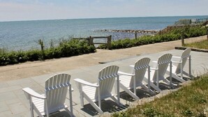 A row of white Adirondack chairs facing a beach with a clear view of the ocean. - Ocean Front, Private Beach, Ocean View , Private patio (Dennis)