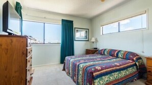 Un dormitorio con una cama grande, un aparador, una ventana y un cuadro en la pared.
