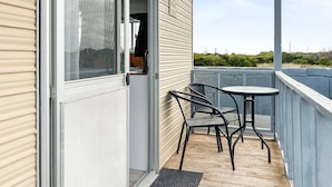En balkong med ett bord och stolar, en skjutdörr i glas och utsikt över landskapet.