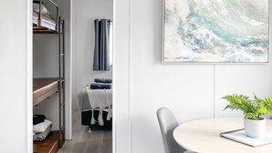 Ett modernt rum med våningssängar, ett runt bord med en växt och en stor, abstrakt målning.