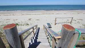 A wooden boardwalk leading to a sandy beach with the ocean in the background.