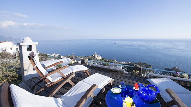 A terrace with lounge chairs and a table set for a meal, overlooking a coastal view. - Incredible location in  Amalfi Coast, with amazing view to detox body and soul (Conca dei Marini)