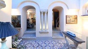 A spacious atrium with a tiled floor, a central column, and a staircase leading to another level. - Incredible location in  Amalfi Coast, with amazing view to detox body and soul (Conca dei Marini)