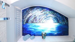 A bathroom with a large blue mural, a white bathtub, and a green vase. - Incredible location in  Amalfi Coast, with amazing view to detox body and soul (Conca dei Marini)