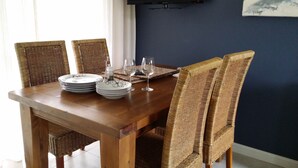 A wooden dining table with wicker chairs, plates, and wine glasses set for a meal. - Highfields Country group Cottage  2 Bedroom (Kurrajong)