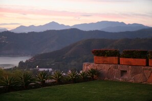 A landscaped garden with a stone wall and potted plants, overlooking a mountainous landscape and a body of water. - Luxury Villa featured in Architectural Digest (Valle de Bravo)