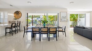Une cuisine moderne avec un coin repas, de grandes fenêtres et une vue sur l’extérieur.
