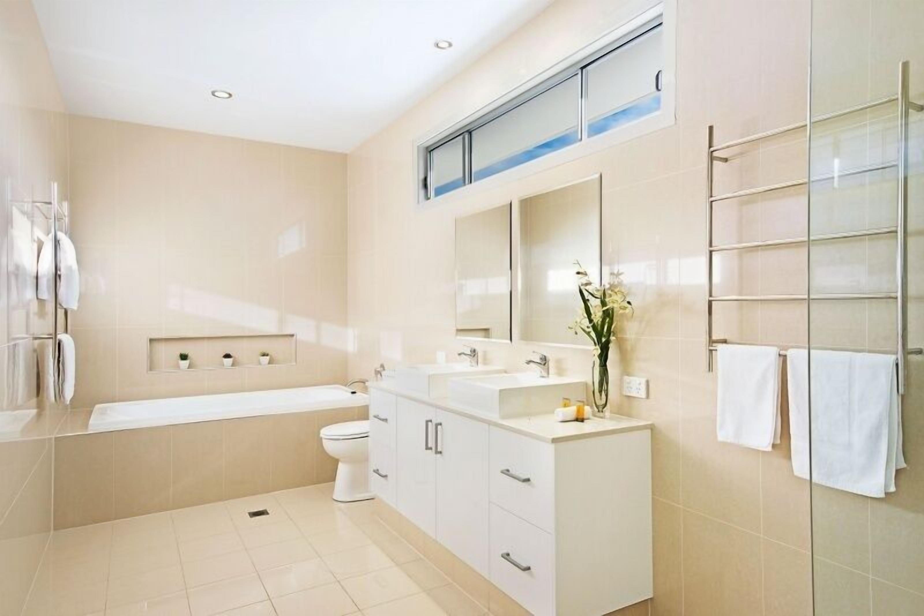 Une salle de bain moderne avec un grand miroir, une baignoire et des toilettes.