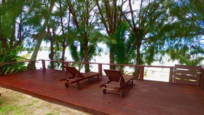 Une terrasse en bois avec deux chaises longues et une rambarde.