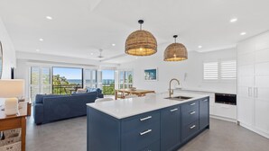 A modern kitchen with a central island, white cabinetry, and a dining area with a blue sofa.