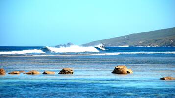 Experience the serene coastal landscape with its rugged shoreline and distant hills.