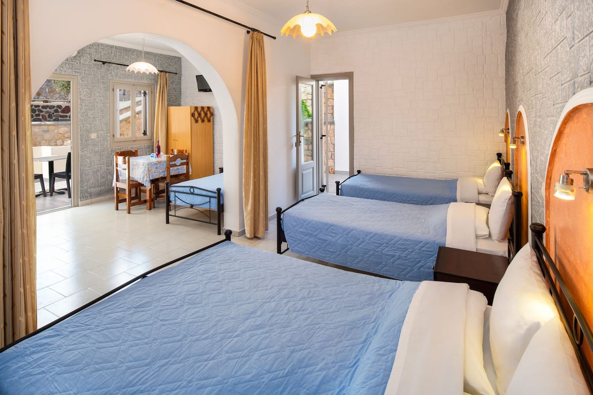 A hotel room with two beds, a dining area, and a bathroom with a mirror and towel rack.