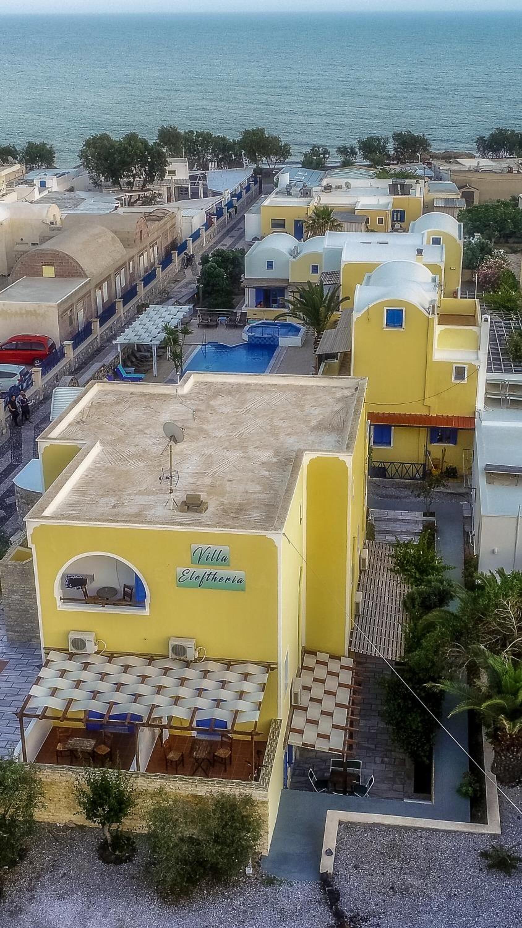 Un hotel costero con varios edificios amarillos, una piscina y vistas al mar.